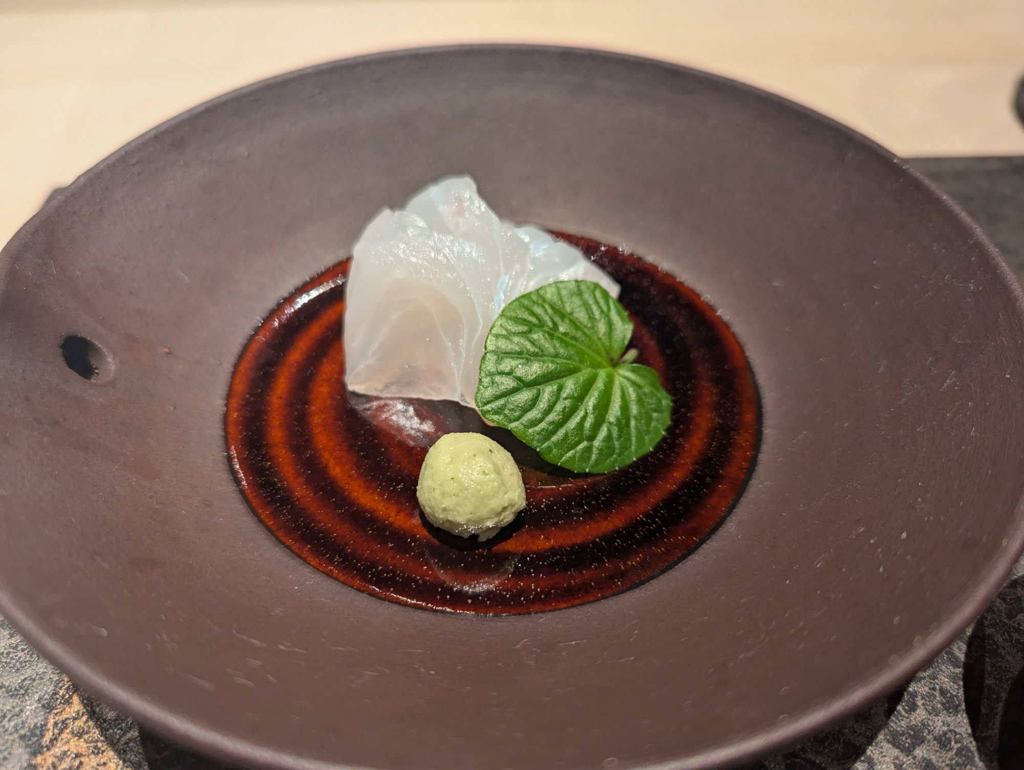 造里。唐津の目一鯛。伝作窯の黒い器の上で、薄造りが透けるように輝く